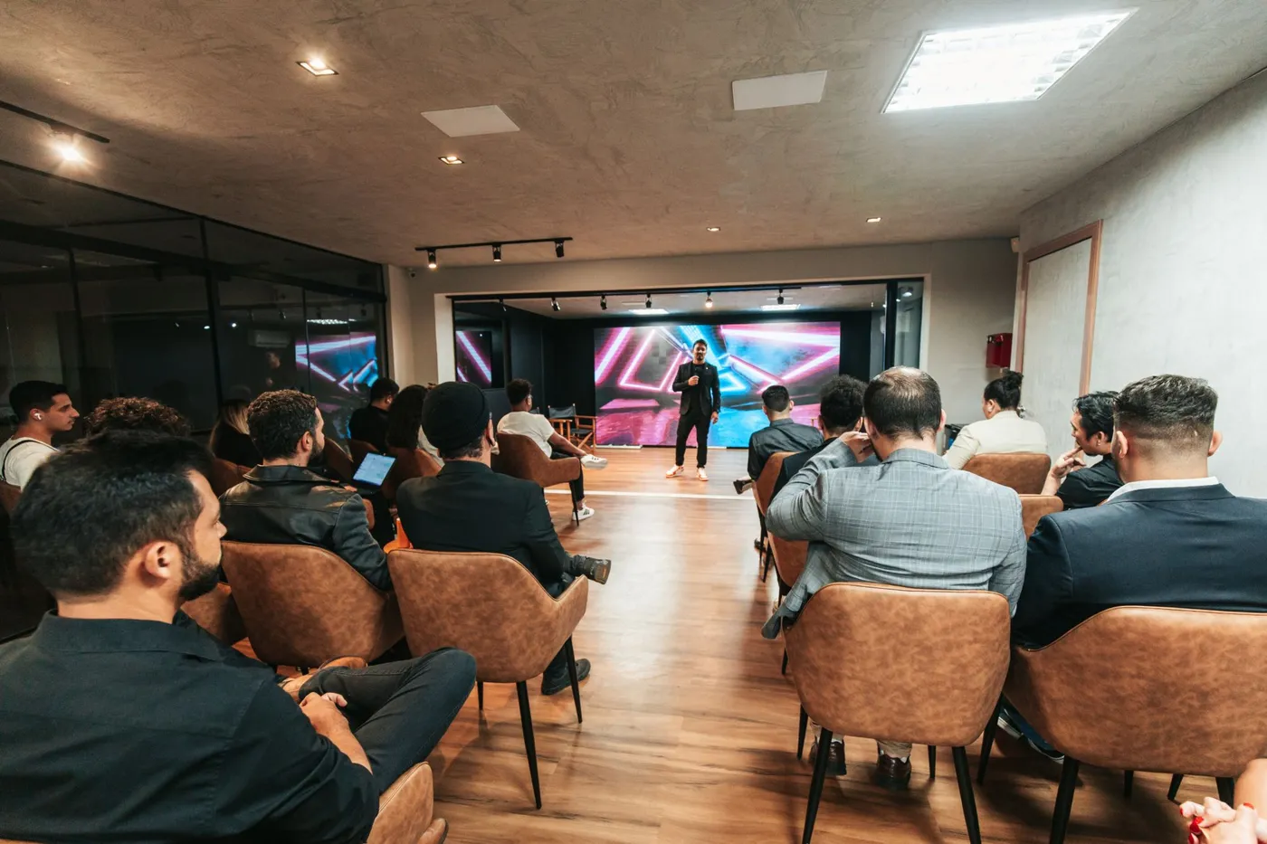 Palestrante no palco falando para a plateia em um evento da Bagin