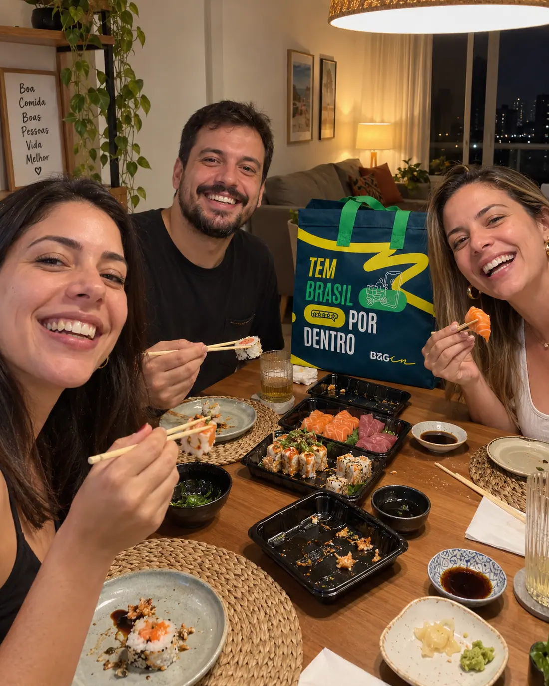 Amigos à mesa com comida japonesa e a Bagin ao fundo