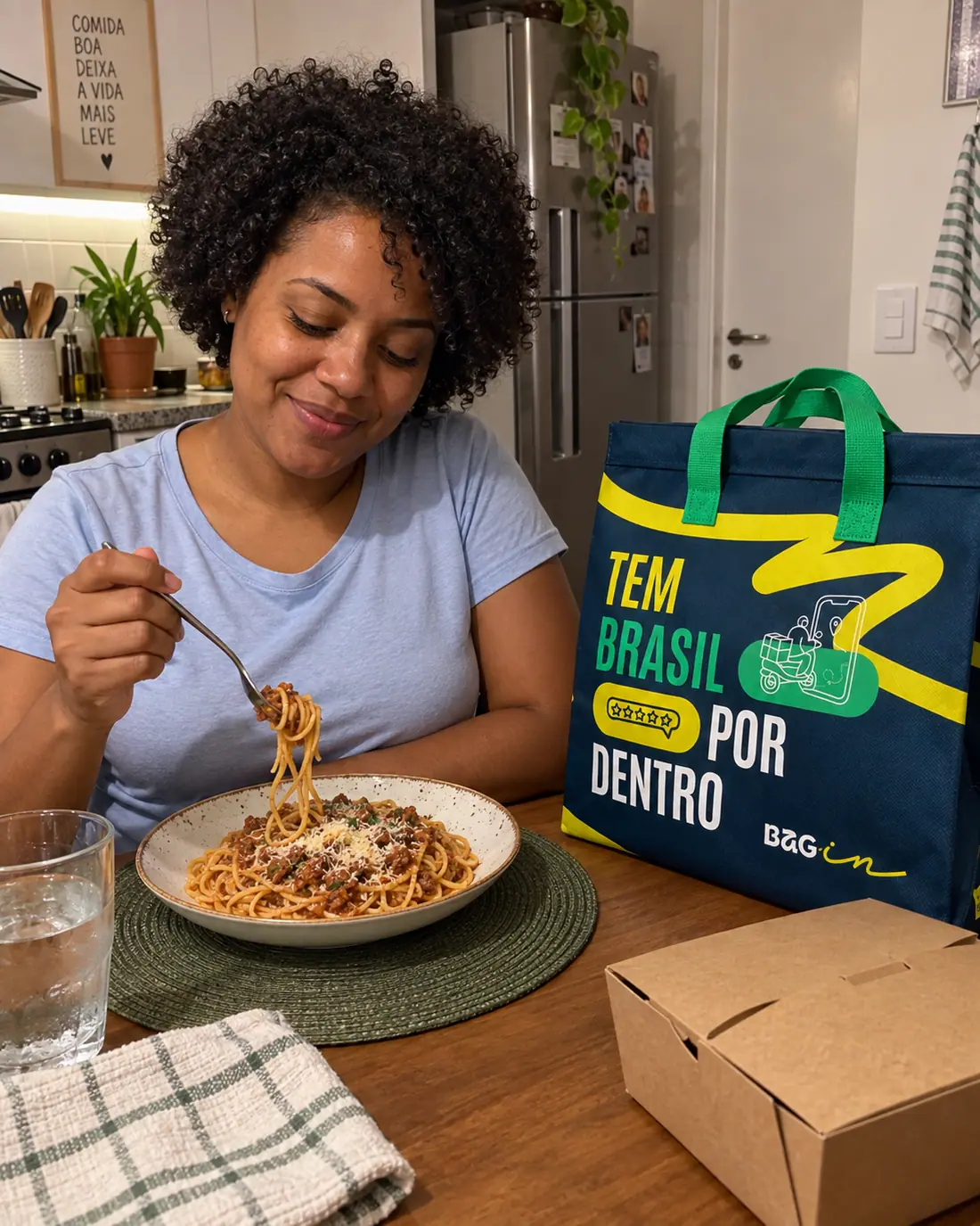 Mulher saboreando uma macarronada em casa, com a Bagin Tem Brasil por dentro ao lado